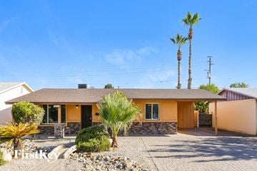 Phoenix house for rent - a yellow house with palm trees and a driveway