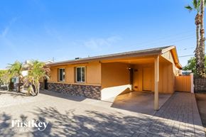 Phoenix house for rent - a yellow house with a driveway and a palm tree