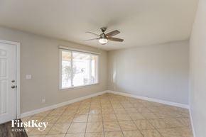 Phoenix house for rent - an empty living room with a ceiling fan and a window