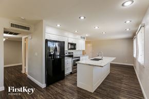 Phoenix house for rent - a kitchen with white cabinets and a black refrigerator
