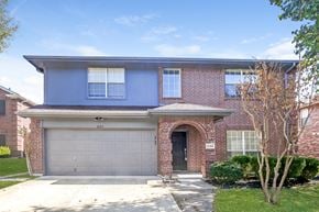 Rockwall house for rent - the front of a brick house with a white garage door