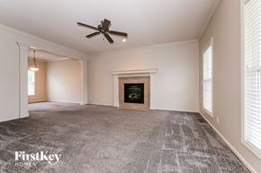 Olathe house for rent - A spacious room with a fireplace and a ceiling fan.