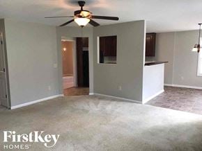 Dacula house for rent - an empty living room with a ceiling fan and a kitchen