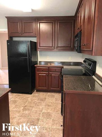 Dacula house for rent - a kitchen with dark wood cabinets and a black refrigerator