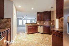 Humble house for rent - a kitchen with brown cabinets and a white counter top
