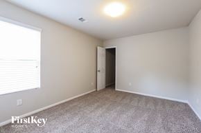 Humble house for rent - a spacious room with carpeted flooring and a large window