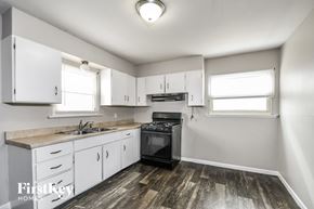 Florissant house for rent - a kitchen with white cabinets and a black stove top oven