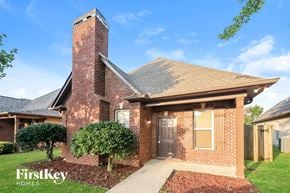 Moody house for rent - A brick house with a chimney and a tree in front.