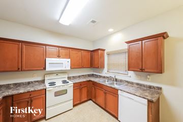 Moody house for rent - A kitchen with wooden cabinets and a white stove top oven.
