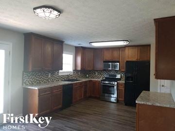 Mcdonough house for rent - A kitchen with wooden cabinets and black appliances.