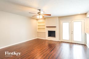 Katy house for rent - an empty living room with a fireplace and a ceiling fan