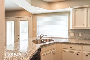 Katy house for rent - a kitchen with white cabinets and a granite counter top and a sink