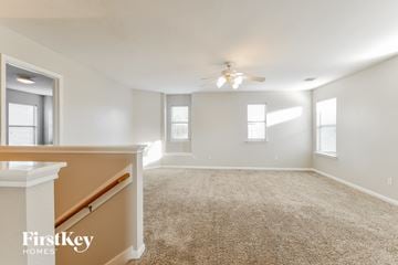 Humble house for rent - a spacious living room with carpet and a ceiling fan