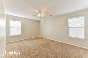 Humble house for rent - a bedroom with carpet and a ceiling fan and two windows