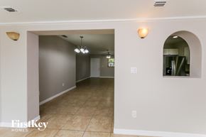 Margate house for rent - A spacious room with a tiled floor and a large arched doorway leading to another room.