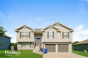 Peculiar house for rent - A two-story house with a garage and a blue trash bin in front.