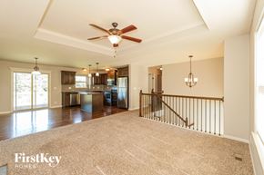 Peculiar house for rent - A spacious living room with a staircase and a ceiling fan.