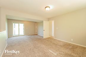 Peculiar house for rent - A spacious room with a carpeted floor and a window with blinds.