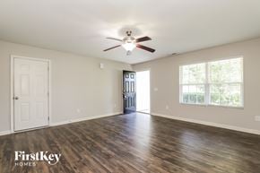Greensboro house for rent - A spacious room with a ceiling fan and wooden flooring.