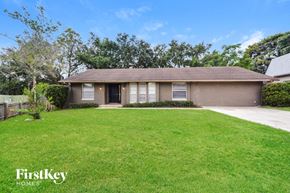 Orlando house for rent - a small brown house with a lawn and a driveway