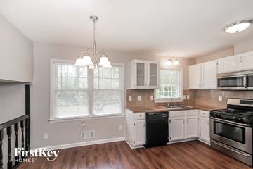 Lawrenceville house for rent - a kitchen with white cabinets and black appliances