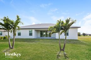 Cape Coral house for rent - A white house with a grey roof and two palm trees in front.