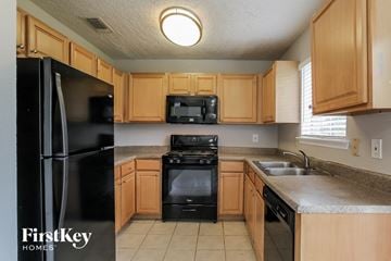 Katy house for rent - a kitchen with wooden cabinets and black appliances