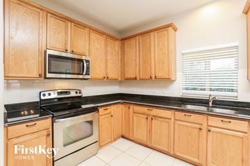 Apopka house for rent - a kitchen with wooden cabinets and a stove and microwave