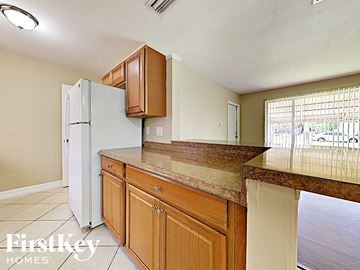 Port Charlotte house for rent - A kitchen with a white refrigerator and wooden cabinets.