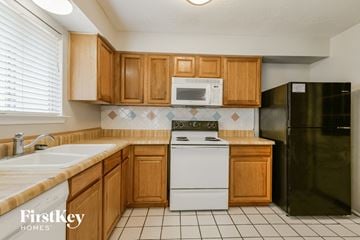 Spring house for rent - A kitchen with wooden cabinets and a black refrigerator.