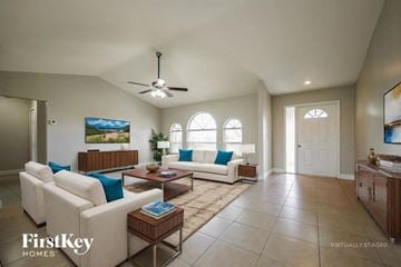 Cape Coral house for rent - A spacious living room with a white sofa set and a ceiling fan.