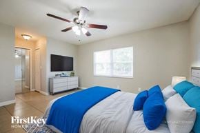 Cape Coral house for rent - A bedroom with a bed, a ceiling fan, and a television.