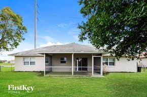 Cape Coral house for rent - A house with a white exterior and a grey roof is surrounded by a grassy lawn.