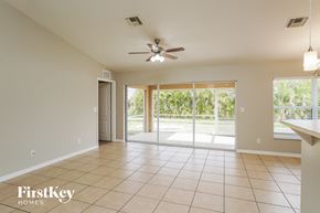 Cape Coral house for rent - A spacious room with a ceiling fan and sliding glass doors leading to a garden.