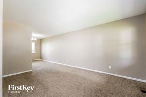 Florissant house for rent - A spacious room with a carpeted floor and white walls, with a window on the left side.