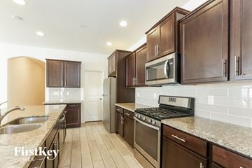 Buckeye house for rent - A kitchen with brown cabinets and a black stove top oven.