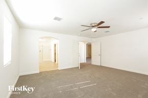 Buckeye house for rent - A spacious room with a fan and carpeted floor.