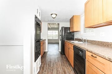 Spring house for rent - A kitchen with wooden cabinets and black appliances.