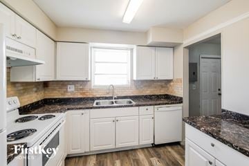 Miami Gardens house for rent - A kitchen with white cabinets and a black countertop.