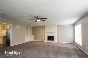 Spring house for rent - an empty living room with a fireplace and a ceiling fan