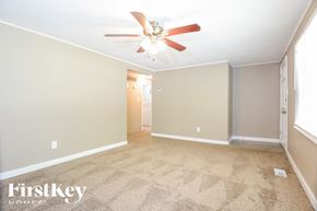 Arnold house for rent - A carpeted room with a ceiling fan and a door in the background.