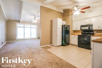 Gladstone house for rent - a kitchen with white cabinets and black appliances