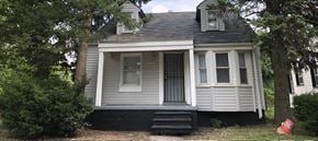 Detroit house for rent - A small house with a grey front and a black door.