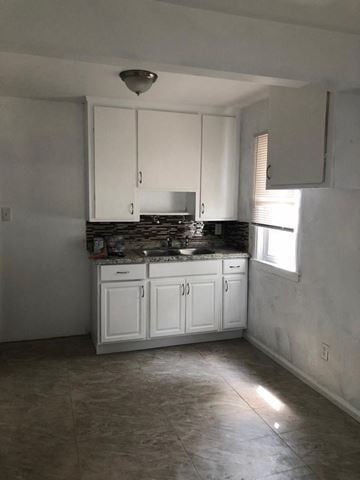 Detroit house for rent - A kitchen with white cabinets and a black countertop.