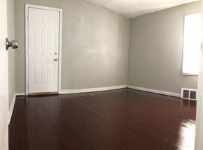 Detroit house for rent - A room with a white door and wooden floor.