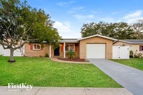 Largo house for rent - a beige house with a driveway and a tree