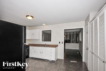 Florissant house for rent - A kitchen with white cabinets and a black refrigerator.