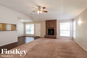 Friendswood house for rent - an empty living room with a fireplace and a ceiling fan