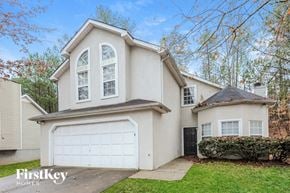 Atlanta house for rent - A house with a garage and a tree in front of it.