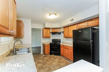 Atlanta house for rent - A kitchen with wooden cabinets and a black refrigerator.